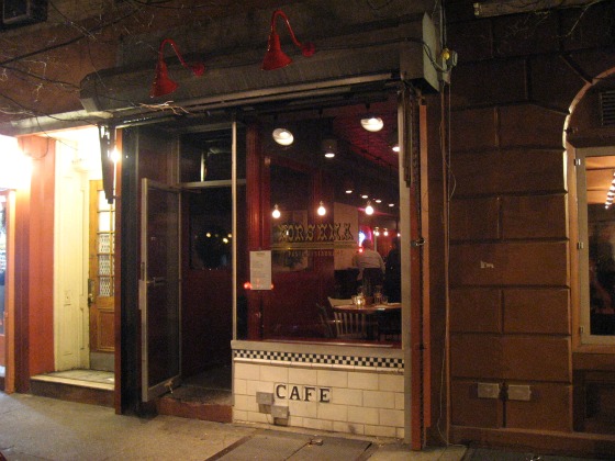 Porsena NYC exterior with red antique lights, a big open window and cafe etched into the stonework outside