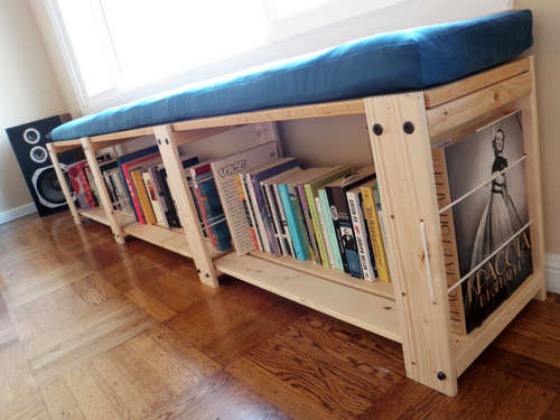 ikea-hack-storage-solution-bookshelf-bench An IKEA hacked shelf for books running the length of a window with a blue cushion on top and a speaker in the corner, all shot at an angle