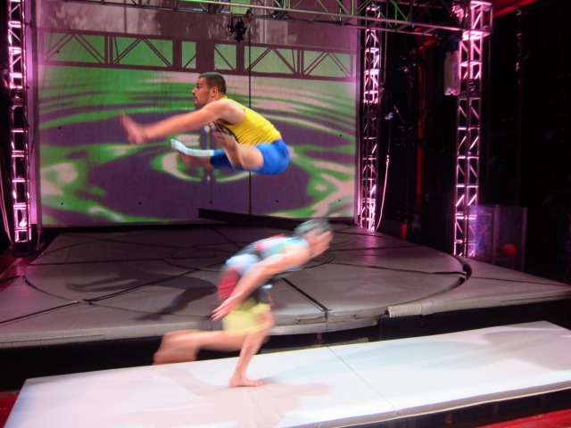 Action shot of two members of Streb Company crashing into one another, but just barely missing as one jumps over the other