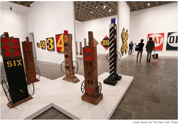 A section of Robert Indiana's Whitney exhibition with numbers and words in bright colors on the walls and pillars with wheels