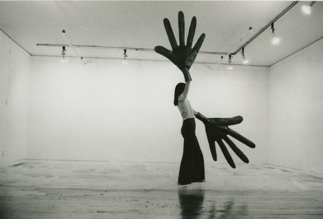 Image of a women in a black skirt wearing and waving giant black gloves