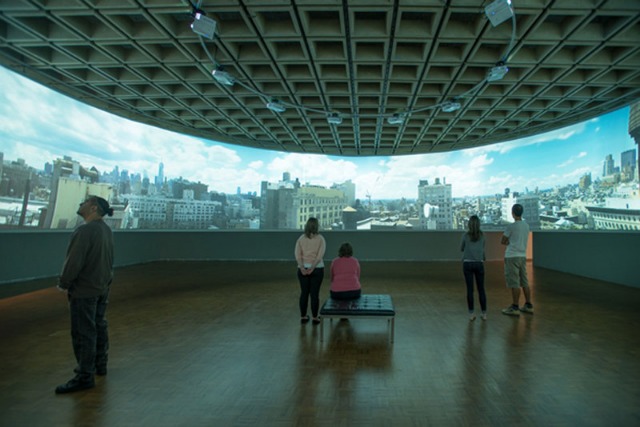 Image of people at the Whitney looking at T.J. Wilcox's 360 degree video panorama of the city