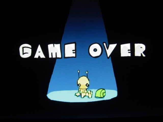 Image of the "Game Over" screen of the Alein Hominid video game with an alien sitting under a spotlight