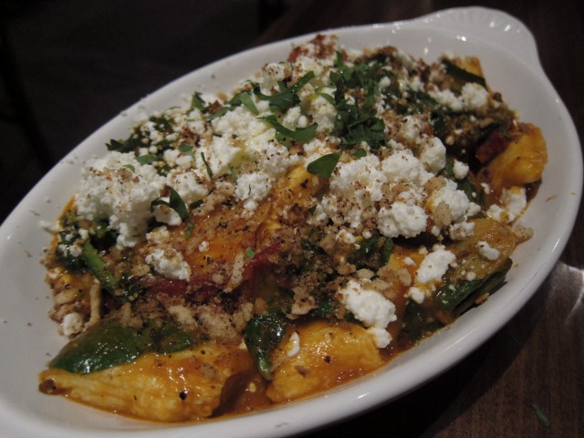 Kefi's Sheep Milk Dumplings, a casserole dish with spicy lamb sausage, chunks of feta, tomato sauce, spinach, crunchy pine nuts, and garlic