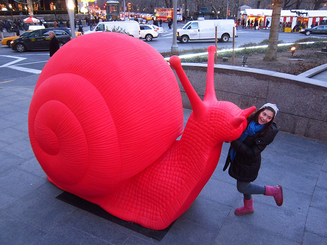Young girl poses next to one of the big red snails in columbus circle