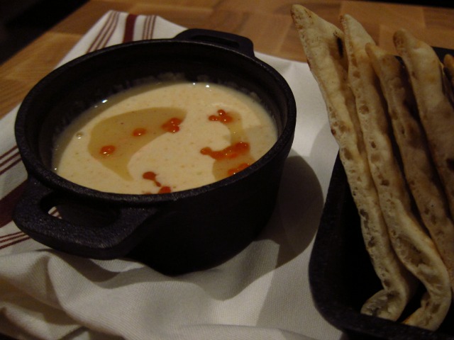 Image of a black bowl with a creamy dip and pita bread off the menu of Snak EOS