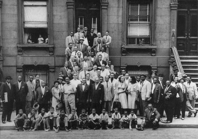 Vintage, black and white photograph of a group of African American men, women, and children posing for the picture.