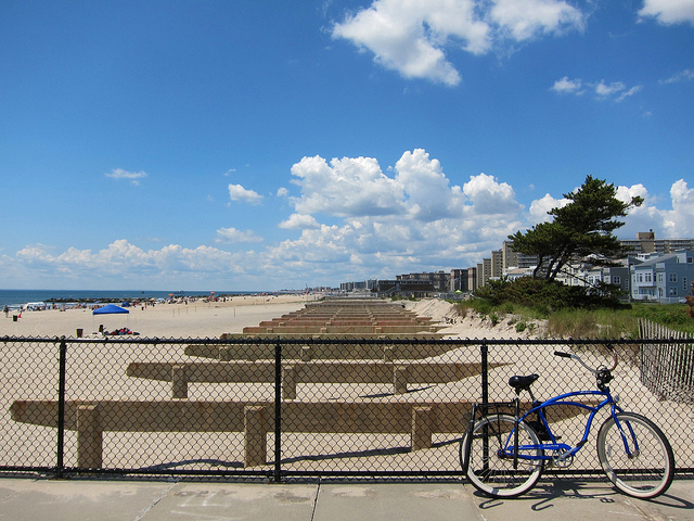 Image of a clear blue sky at the beach with a bike sitting against the fence