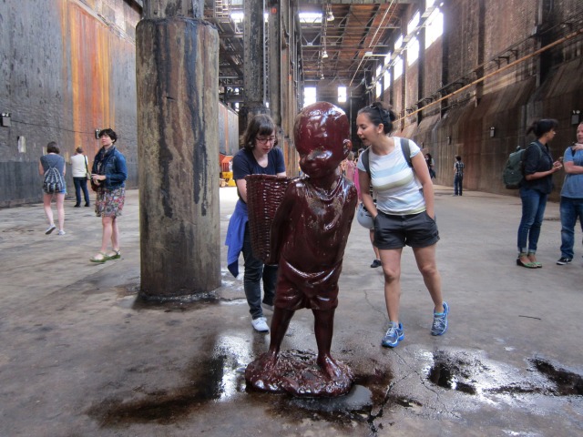 Inside Domino Sugar Factory people walk around to look at all of Kara Walker's sugar statutes