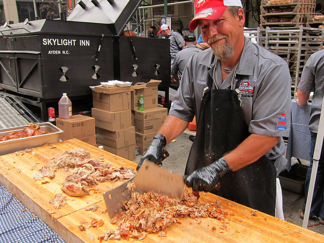 Man working the Big Apple BBQ in NYC by cutting up smoky meat