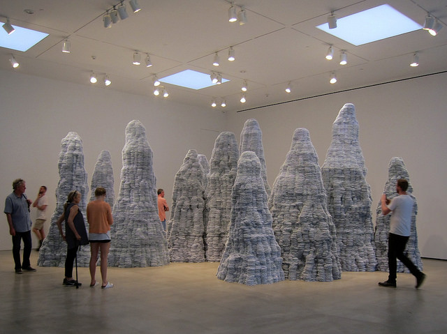 Tara Donovan's index card sculptures standing in a group together looking like stalagmites in a cave