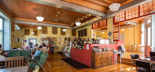 An inside look of Peekskill Coffee House with vintage blue chairs and a red barista counter top.