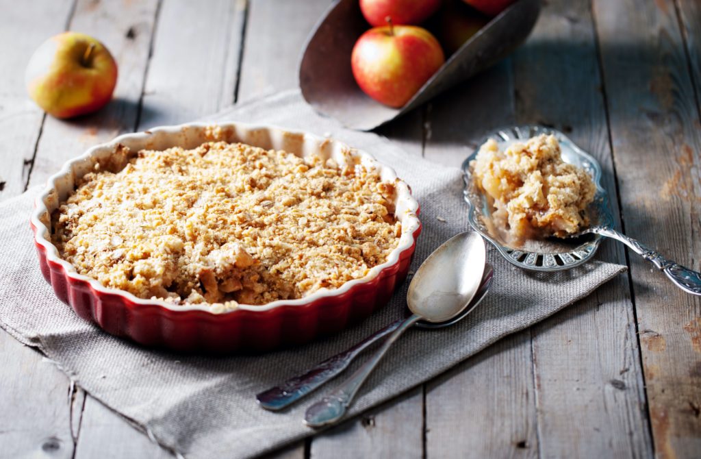 Apple crisp in a dish with apples in the background