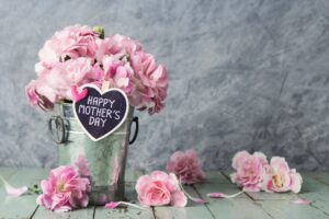 Pink carnation flowers in zinc bucket with happy mothers day letter on wood heart