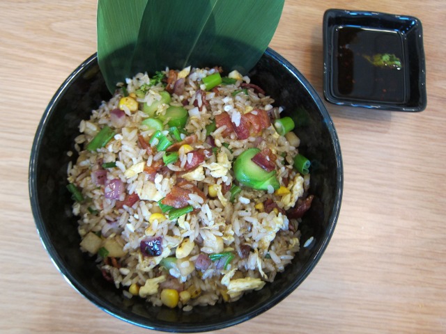 Neuske's Bacon and Egg Fried Rice stirfry in a big black bowl with a leaf as a garnish